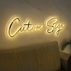 the custom sign is lit up on the wall next to a couch and potted plant