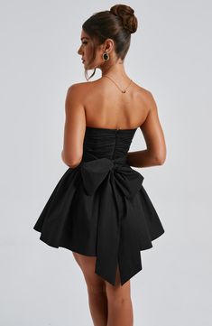 THE dress of the season has landed and you're going to be obsessed. Meet Katrina, our dreamy mini with a pretty, voluminous skirt and waist cinching bodice. Fastening with a zip to the back, tie with an oversized bow to complete the look for perfect feminine drama. 



Colour: Black.

Premium non-stretch cotton blend fabric.

Fully lined.

Strapless ruched bodice with boning.

Waist cinching.

Oversized tie to create bow detail to back.

Voluminous skirt with tulle lining.

Zip fastening to the reverse.

Mini length.

 Size: XS, S, M, L, XL, XXL Black Bow Dress, Voluminous Skirt, Split Long Dress, Desi Fashion Casual, Loungewear Dresses, Maxi Dress Sale, Maxi Dress Navy, Ruched Bodice, Desi Fashion