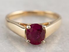 A classic solitaire engagement ring, this ring has lovely presents on the finger, worn alone or with other pieces. We've added a brilliant, oval cut ruby with wonderful depth of color. Meant to be an engagement ring, and is well suited to the job, but one shouldn't be afraid to wear it as an everyday ring, or stacked with other rings! The simple style lends itself to a variety of ways to wear it, with the centerpiece always remaining the brilliant red stone. Metal: 14K Yellow Gold Gem: Ruby .69 Oval Brilliant Cut Ruby Promise Ring, Oval Ruby Solitaire Ring, Classic Ruby Birthstone Ring, Oval Ruby Ring For Proposal, Classic Ruby Ring With Tension Setting For Gift, Classic Ruby Ring With Tension Setting, Classic Ruby Ring With Tension Setting As Gift, Classic Round Ruby Ring With Tension Setting, Classic Ruby Ring With Center Stone