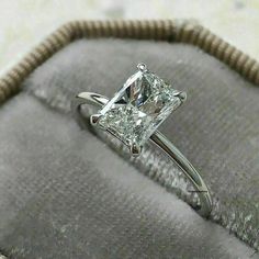 a princess cut diamond ring sitting on top of a cushion