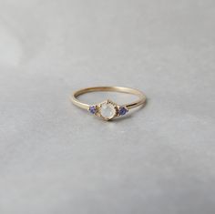 a gold ring with an opal and tan sapphire stones on the side, sitting on a white surface