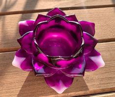 a purple glass flower sitting on top of a wooden table next to a metal object