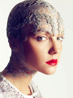 a woman with red lips wearing a white dress and veiled headdress is looking off to the side