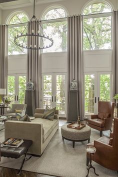 a living room filled with lots of furniture and large window covered windows over the top of them