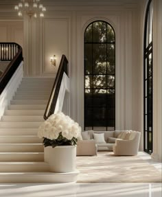 an elegant staircase with white flowers and chandelier in the background, leading up to a sitting area