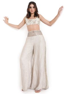 Off white georgette embroidered choli and tissue pant with mirror belt. Disclaimer: Since we are a made-to-measure brand and our dyeing process and embroidery are handcrafted, there may be slight variations in the color and embroidery of the actual product. The print placement may also vary from what is represented in the images shown on the product page. Designer Wear Fitted Palazzo Set With Straight Pants, Designer Fitted Palazzo Set With Straight Pants, Festive Designer Pants With Mirror Work, Fitted Pant Set With Gota Work, Bollywood Style Festive Bottoms With Mirror Work, Festive Bollywood Bottoms With Mirror Work, Elegant Festive Bottoms With Mirror Work, Bollywood Wedding Pants With Chikankari Embroidery, Elegant Bottoms With Mirror Work For Festive Occasions