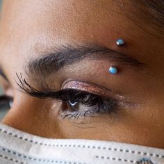 a woman's eye with some piercings on her forehead and under the eyes