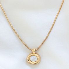 Elevate your everyday look with this gold-filled Molten Bezel Necklace, featuring a lustrous shell pearl at its center. The unique molten bezel design adds a modern, organic touch that makes this necklace stand out. Perfect for layering with other necklaces or wearing on its own for a minimalist statement. 14k Gold Filled Chain 24k Gold Filled Molten Bezel Charm: 21mm x 19mm Chain length: 16", 18", 20" Lobster clasp closure for secure wear Hypoallergenic, perfect for sensitive skin Water resista Modern Gold Pearl Necklace With Pendant, Modern Gold Pearl Necklace With Pearl Charm, Modern Gold Necklace With Pearl Chain, Elegant Shell Necklace With Round Pearl Pendant, Elegant Gold Shell Necklace With Clavicle Chain, Elegant Gold Shell Necklace With Pearl Charm, Elegant Gold Shell Necklace With Pearl Drop, Elegant Gold Round Shell Necklace, Elegant Gold Shell Necklace With Round Pendant