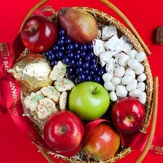 a basket filled with lots of different types of fruit and sweets on top of a red table