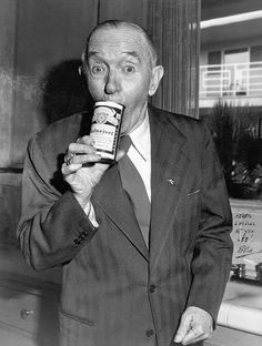 an old man in a suit drinking from a bottle