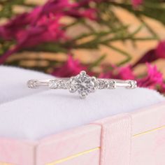 a diamond engagement ring sitting on top of a pink box with flowers in the background