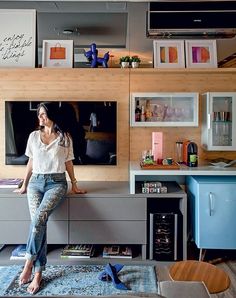 a woman sitting on top of a counter in front of a tv mounted to the wall