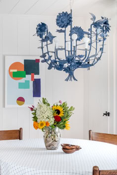 a vase with flowers sitting on top of a table next to a chandelier