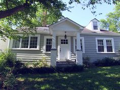 a small gray house sitting in the grass