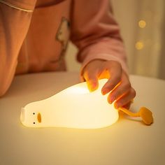 a child's hand reaching for a light that is shaped like a bear on a table