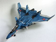 a blue fighter jet sitting on top of a white table