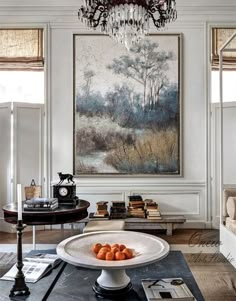 a living room filled with furniture and a chandelier hanging from the ceiling next to a painting