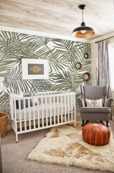 a baby's room with palm leaves on the wall and a white crib