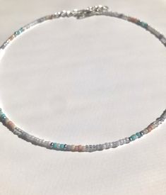 This dainty Seed Bead Choker Necklace is made with pretty multi-colored glass seed beads. The main color is pearly white that is paired well with a hint or teal and light pink seed beads. The tiny seed beads are strung on beading wire & finished with a silver plated lobster style clasp with a 2 inch extension chain, to allow for personal size adjustments. These necklaces are perfect for everyday wear. Enjoy a simple, boho /chic yet minimalist look with a single strand or layer them with some Pastel Beaded Necklaces With Colorful Beads As Gift, Pastel Beaded Necklaces With Colorful Beads For Gifts, Pastel Beaded Necklaces With Round Beads, Pastel Beaded Necklaces As Gift, Pastel Colorful Beads Necklace For Gift, Adjustable Pastel Beaded Necklaces, Adjustable Pastel Beaded Necklaces With Colorful Beads, Handmade Delicate Beaded Necklaces With Round Beads, Delicate Handmade Beaded Necklaces With Round Beads