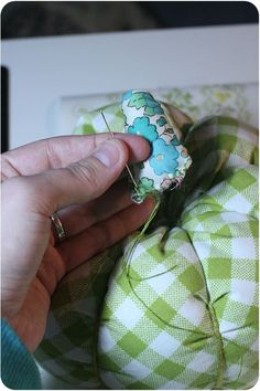 someone is stitching fabric on the back of a green and white chair