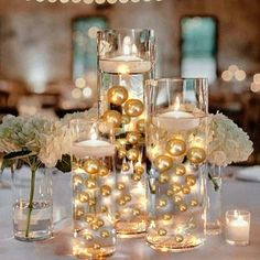 the centerpieces are filled with candles and balls in glass vases, along with white hydrangeas