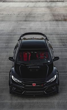 the front end of a black sports car with its hood open on an airport runway