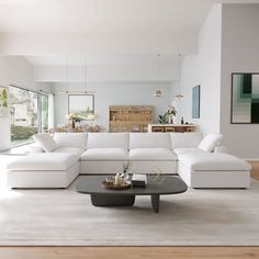 a living room with white furniture and large windows