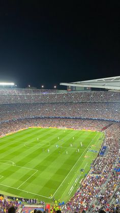 a stadium filled with lots of people watching a soccer game on the field at night