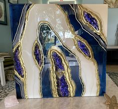 a blue and white abstract painting with gold accents