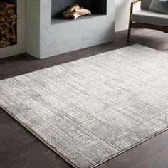 a living room area with a fireplace, chair and rug in front of the fire place