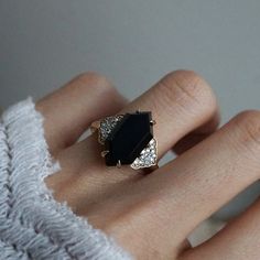 a woman's hand with a black and white diamond ring on top of it