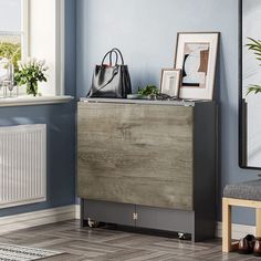 a wooden cabinet sitting next to a window in a blue room with pictures on it