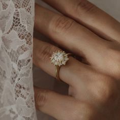 a woman's hand wearing a gold ring with diamonds on it and white lace