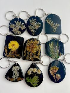 a bunch of different types of flowers on black glass keychains with silver accents