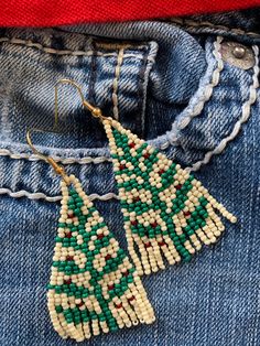 the beaded christmas tree earrings are hanging from jeans