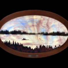 a wooden plaque with an image of a lake and trees in the sky on it