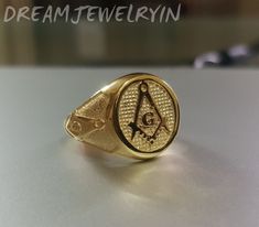 a gold ring with an eye and masonic symbol on the front, sitting on top of a table