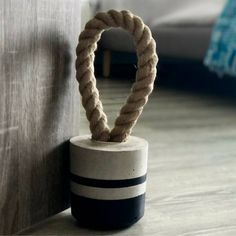 a rope wrapped around a cement container on the floor next to a wall and bed