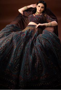 a woman sitting on top of a bed wearing a dress and headpiece with an intricate pattern