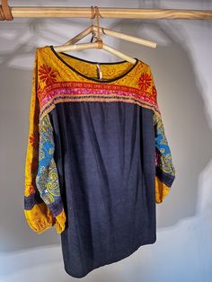 Free People patterned and embroidered long-sleeve shirt. The sleeves balloon or are slightly flared but gather at the three-quarter length close to the wrists. The base of the shirt is a soft navy blue cotton and the material of the shirt hangs loosely on the body in a flattering and casual fashion. This shirt can be styled up or down. Great for transition seasons. Fall Cotton Blouse With Embroidered Cuffs, Long Sleeve Cotton Blouse With Embroidered Cuffs, Long-sleeved Cotton Blouse With Embroidered Hem, Long Sleeve Cotton Blouse With Embroidered Hem, Long Sleeve Cotton Embroidered Top, Bohemian Cotton Blouse With Embroidered Cuffs, Cotton Blouse With Embroidered Hem And Long Sleeves, Folk Style Embroidered Hem Long Sleeve Peasant Top, Folk Style Long Sleeve Peasant Top With Embroidered Hem