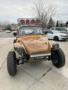 an old style buggy is parked in a parking lot with other cars behind it