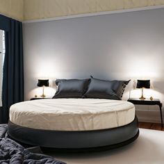 a large bed sitting in the middle of a bedroom next to two lamps on either side of it