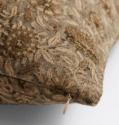 a close up of a pillow on a white surface with a brown and tan pattern