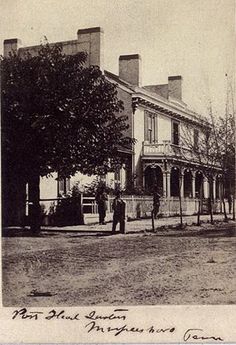 an old black and white photo of people standing in front of a house