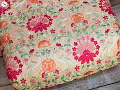 an orange and pink flowered pillow sitting on top of a wooden floor