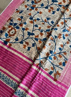 a pink and blue sari with floral designs on the border, sitting on top of a