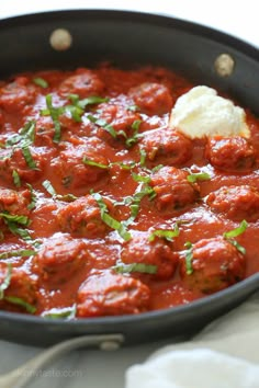 a skillet filled with meatballs covered in sauce and garnished with parsley