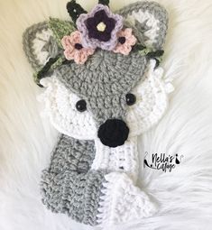 a crocheted stuffed animal with flowers on it's head sitting on white fur