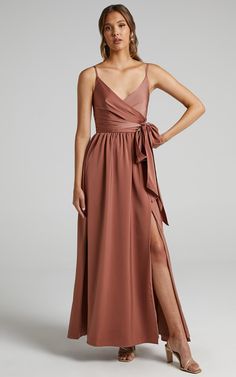 a woman is wearing a long dress with a slit down the side and an asymmetric