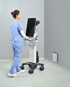 a woman in scrubs standing next to a monitor